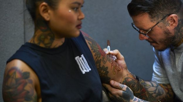 A tattooist draws an image on a customers arm at The London International Tattoo Convention