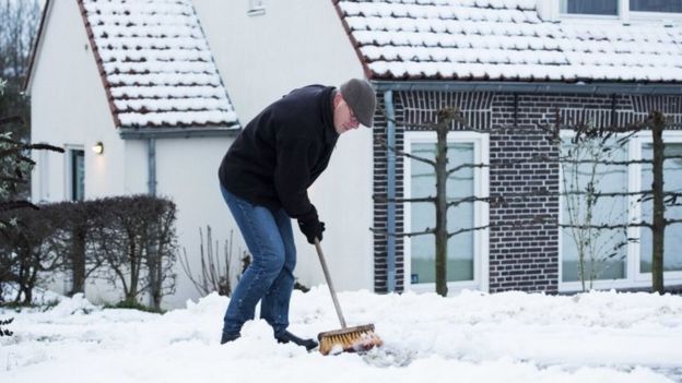 A man clears snow from a path at a house near Nijmegen, in the east of the Netherlands (13 January 2017)