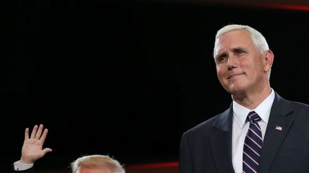 Vice-President Mike Pence, next to the top of Trump's head and his hand, smaller than usual, waving