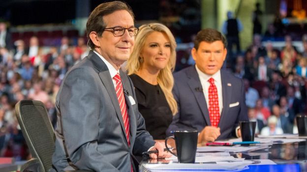 Three moderators, including Ms Kelly, sit at a table during the first Republican debate