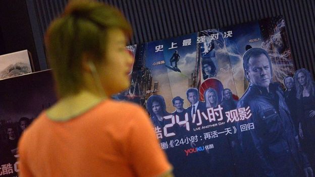 Man walks past a cinema poster where Chinese video-sharing website Youku Tudou, was holding a 24-hour event for the release of the new season of US television show '24' in Beijing