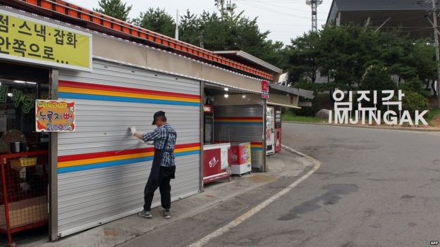 A South Korean man pulls down a shutter of his shop at the Imjingak Peace Park near the Demilitarized zone dividing the two Koreas in Paju on 20 August 2015, as residents of several border villages are ordered to evacuate their homes for nearby shelters