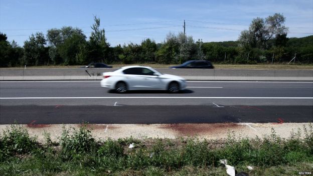 Cars pass the site where a lorry carrying several bodies was found in Austria - 28 August 2015