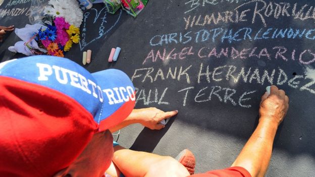 Un hombre escribe los nombres de las víctimas de Orlando con una tiza en el pavimento.