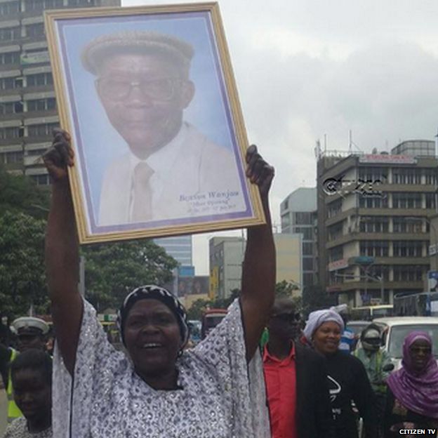 Woman holding up picture of Mzee Ojwang