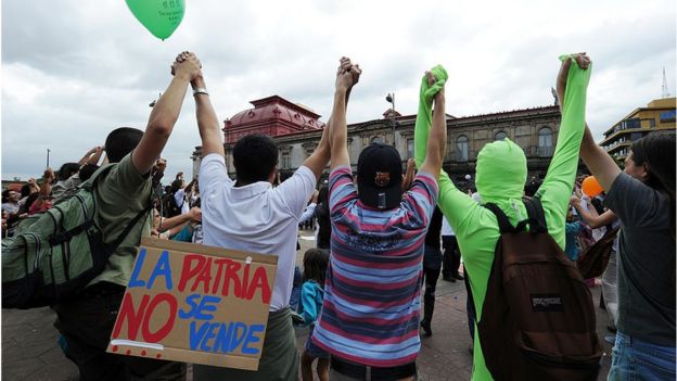 Manifestantes en Costa Rica protestan con un cartel que dice