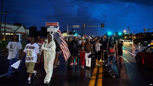 Demonstrators participate in a protest march on West Florissant Avenue in Ferguson, Missouri, marking the one year anniversary of an unarmed black teen, Michael Brown (9 August 2015)