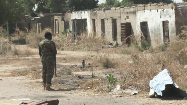 A soldier facing a destroyed building in north-east Nigeria