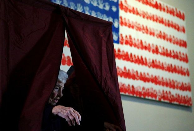 Mujer mayor sale del cubículo después de votar.