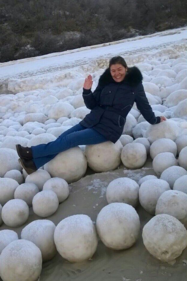 A picture showing a smiling woman lying across the snowballs in the Yamal Peninsula