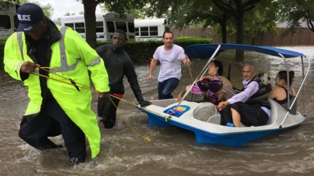 A lone police officer pulls a family to safety from flooding in the western suburbs of Houston on Monday August 28 (pic: James Cook, BBC)