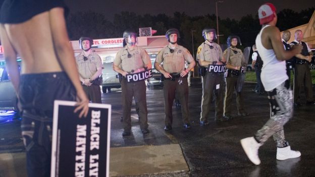 A line of police stand behind protesters in Ferguson, Missouri