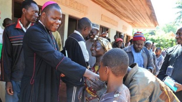 Bangui's archibishop Dieudonne Nzapalainga (L) shakes hands with people after a meeting gathering christian and muslim community members on October 8, 2013 in Bangassou