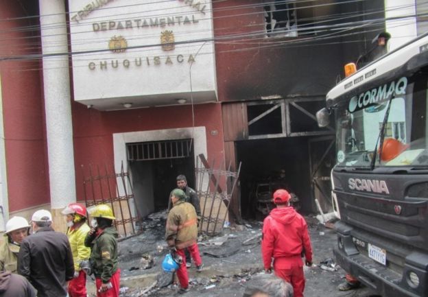 Firefighters work outside the Bolivian electoral office set on fire by protesters on 21 October, 2019.
