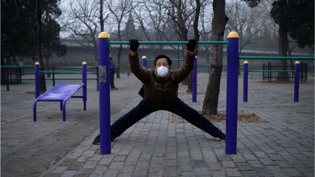 12月20日，北京严重雾霾已持续五天，一位戴口罩的老人在一处公园锻炼。