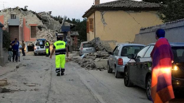 People stand along a road following a quake in Amatrice