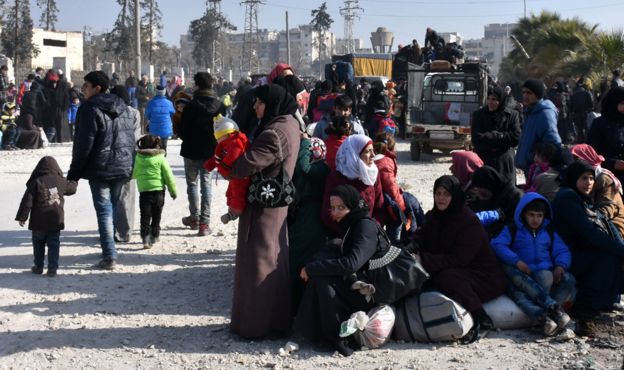 Syrians wait at a checkpoint manned by pro-government forces after leaving eastern Aleppo