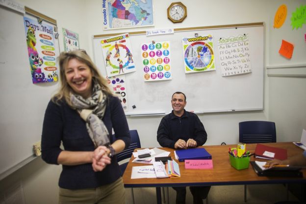 Syrian Refugee Abdel Malek Al-Jasem laughs with his ESL instructor Anu Greenwood, during English lesson