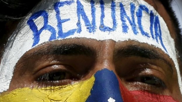 An opposition supporter with his face painted with the colours of the Venezuelan national flag and the word 