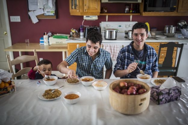 Syrian refugees and brothers, left to right Fadl Al Jasem, Ahmad, and Ramaz eat lunch inside their temporary home in Picton, Ontario, Canada.