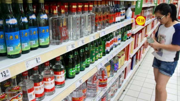 A woman holds a bottle of alcohol product at a supermarket in Nanjing, Jiangsu Province, China, August 6, 2016