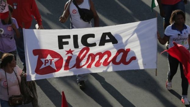 Government supporters carry a sign that says in Portuguese 