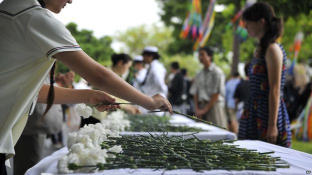 A girl presents a white chrysanthemum flower during a ceremony marking the 70th anniversary of the end of World War 2 on 14 August 2015