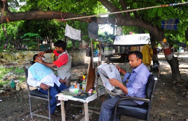 An Indian barber attends to a customer at his roadside hairdresser shop in Allahabad on July 6, 2013.