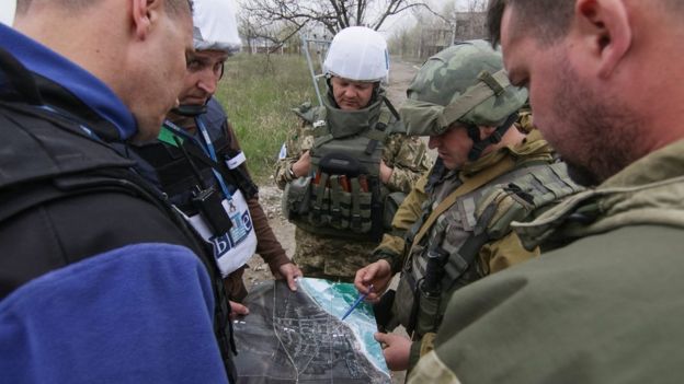 Ukrainian soldiers and monitors look at a map near Mariupol, where an increase in violence is reported (13 April)