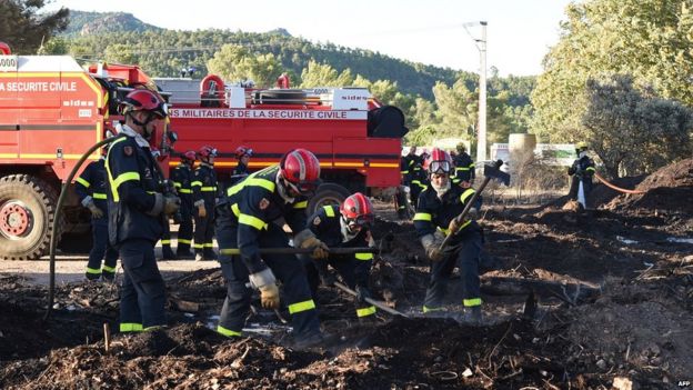 Firefighters inspect a campsite following a wildfire in Bagnols-en-Foret