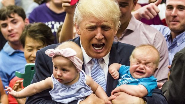 Donald Trump gestures as he holds a crying baby