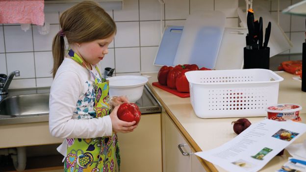 Niña en clase de cocina con un morrón en la mano en Norssi, la escuela normal de la Universidad de Jyvaskyla