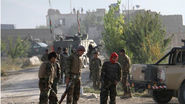 Afghan National Army soldiers stand near the body of a Taliban insurgent outside the prison