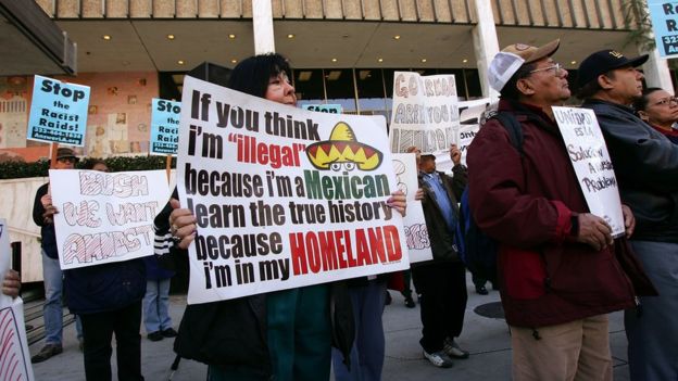 Mujer con cartel en contra de las deportaciones