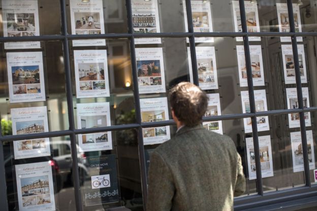 A man looks in an estate agents window