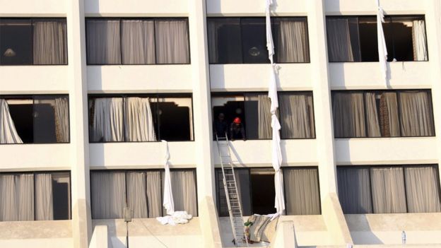 Rescue workers conduct a search operation after a fire in the Regent Plaza hotel - makeshift sheet ropes can be seen hanging from several windows