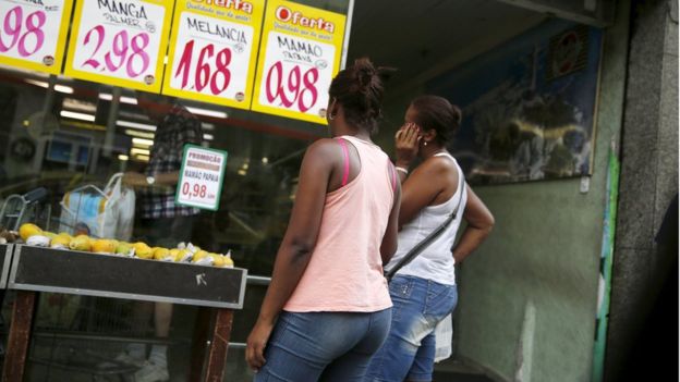 Women look at prices at a food market in Rio de Janeiro, Brazil