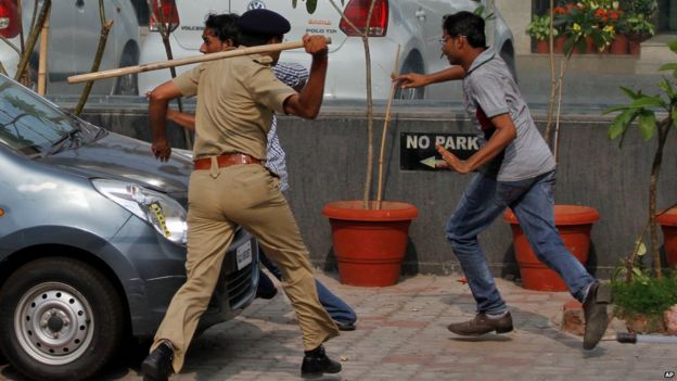 An Indian policeman uses a baton to disperse protesters during a clash between two groups in Ahmadabad, India, Tuesday, Aug. 25, 2015.