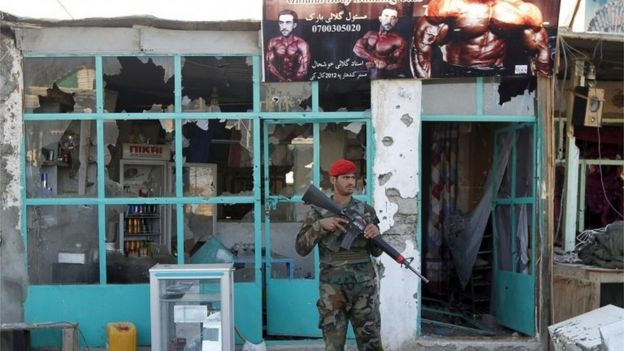 Afghan National Army (ANA) soldiers stand guard in front of a shop burned during the Taliban attack on Kandahar Airport, on 9 December 2015.