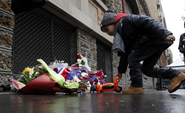 People pay their respects under a commemorative plaque next to the Belle Equipe bar and restaurant, in Paris, France, 13 November