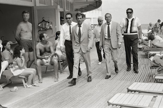 Frank Sinatra with his minders and his stand in (who is wearing an identical outfit to him), arriving at Miami Beach while filming The Lady in Cement