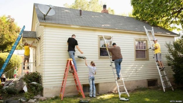 Un grupo pintando el frente de una casa