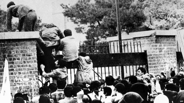 Iranian protesters scale a wall of the US embassy in Tehran on 4 November 1979