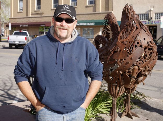 Troy Waters stands next to a statue of Mike in Fruita