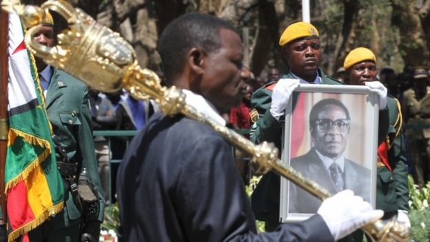 A soldier holds a picture of President Robert Mugabe during the opening of Zimbabwe