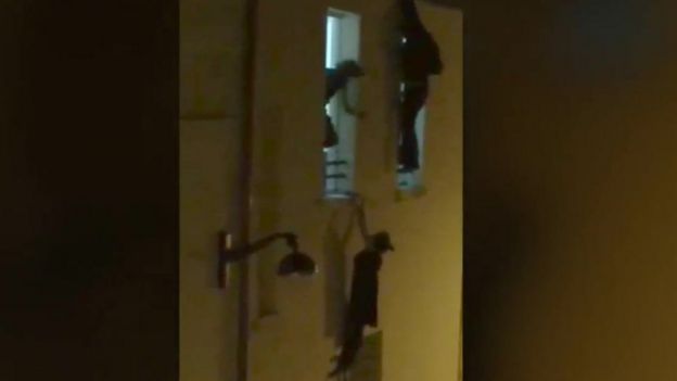A pregnant woman hangs from a window ledge outside the Bataclan