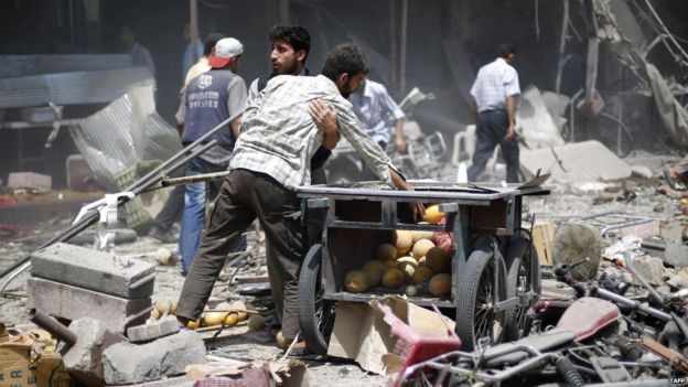 Syrian men stand amid the rubble after what activists said was a government air strike in the rebel-held Damascus suburb of Douma (16 August 2015)