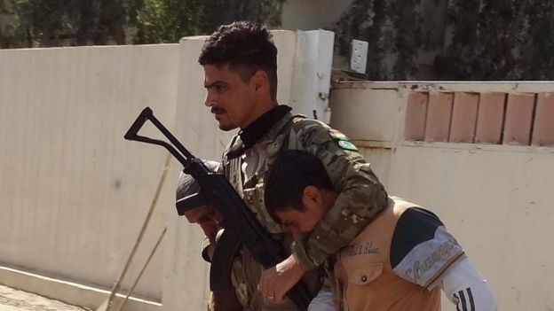 A Kurdish fighter escorts a prisoner in Kirkuk, 22 October
