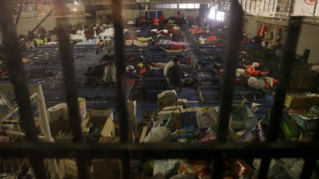 People prepare to spend the night in a makeshift camp set up inside a gymnasium