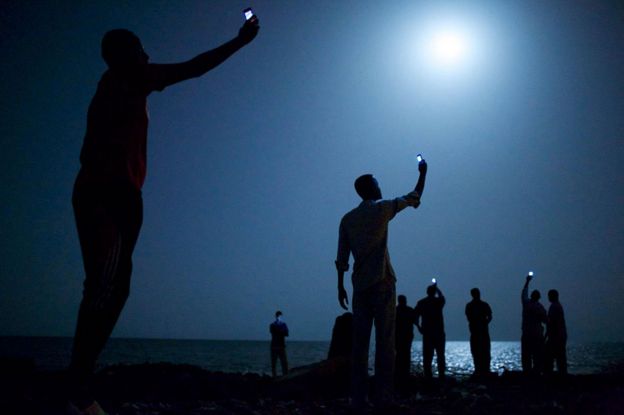 Migrants with mobile phones on the beach in Djibouti